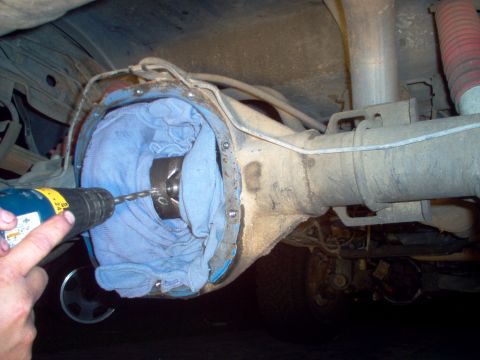 1988 Ford Bronco - A drill bit is used to make a hole in the differential cover, with a blue cloth stuffed inside.