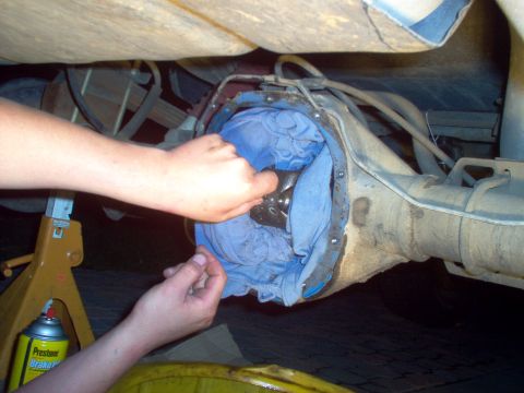 1988 Ford Bronco - Hands work on the internal components of a vehicle's differential after the cover has been removed.