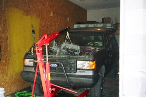 1989 Ford Bronco - 1989 Ford Bronco undergoing engine removal in a garage with an engine hoist.
