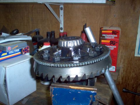 1988 Ford Bronco - Differential gear assembly held in a vise, with various automotive parts and boxes in the background.