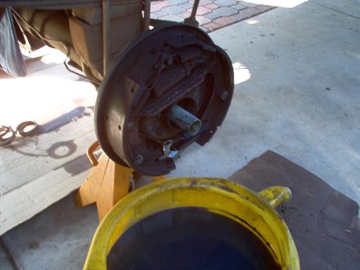 Rear differential brake drum assembly on jack stand, with yellow drain pan