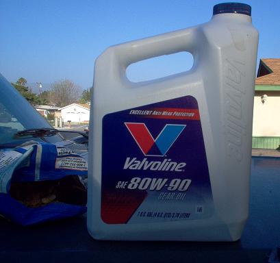 1988 Ford Bronco - A bottle of Valvoline 80W-90 gear oil is placed on a surface, with a car's hood visible to the left.