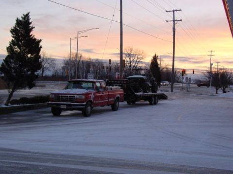 1992 Ford Bronco - A red pickup truck tows a trailer with an ATV on a snowy day at sunrise.
