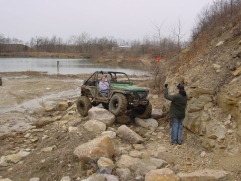 1992 Ford Bronco - Green chopped-top rock crawler built from a small 4x4, climbing limestone boulders at a flooded quarry off-road park while a spotter in a g…