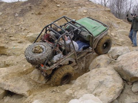 1992 Ford Bronco - An off-road vehicle navigates a rocky terrain, its custom roll cage clearly visible.