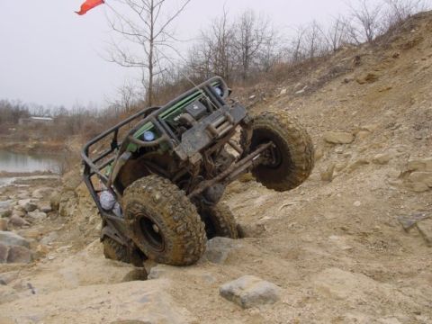 1992 Ford Bronco - This off-road buggy is navigating a challenging rocky terrain, with one wheel lifted high.