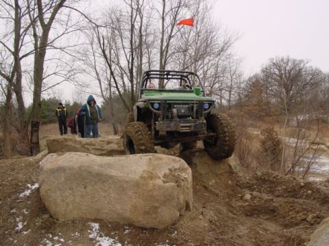 1992 Ford Bronco - This modified off-road vehicle navigates a rocky trail with large tires and a prominent roll cage.