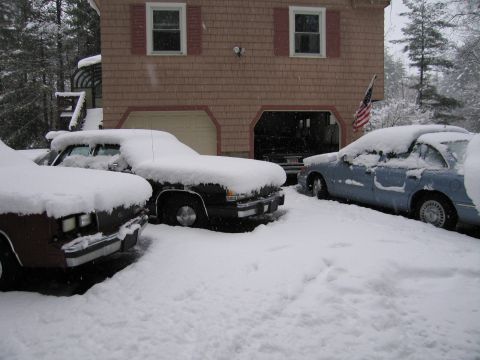2001 Ford Crown Victoria - Multiple vehicles are parked in a snowy driveway in front of a house.