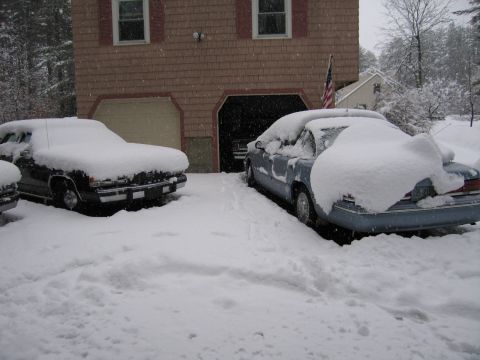 2001 Ford Crown Victoria - Two vehicles are buried in snow outside a garage during a winter storm.