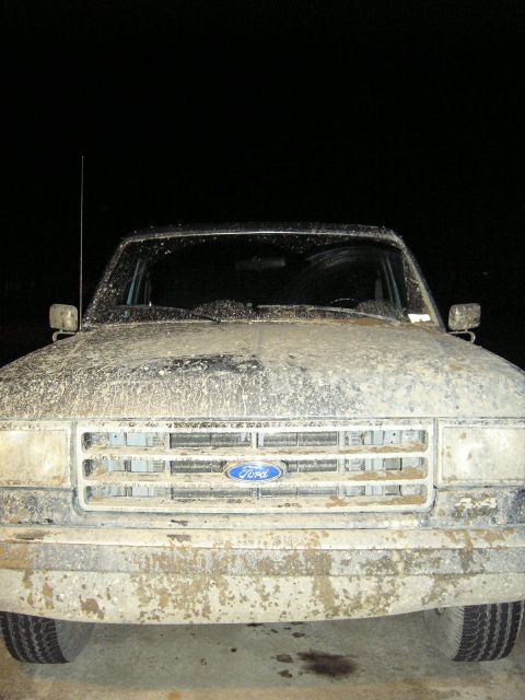 1989 Ford Bronco - Mud-caked 1989 Ford Bronco front view shows grille and headlights.