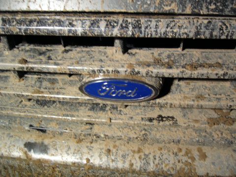 1989 Ford Bronco - The Ford emblem is covered in mud, obscuring the vehicle's specific model and year.