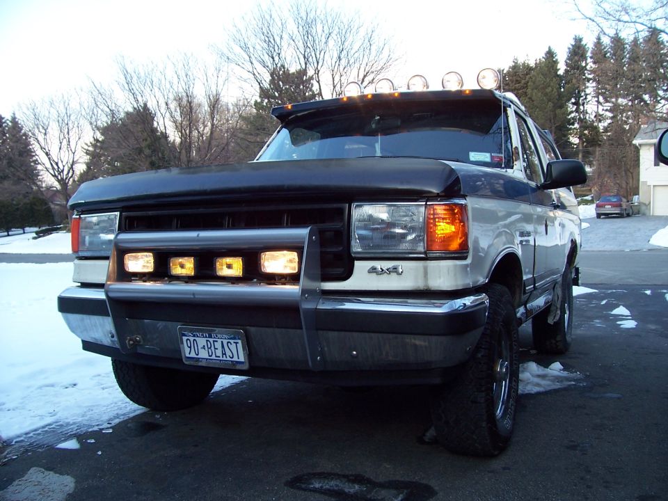 Silver and black Ford 4x4 truck with hood bra, off-road lights, plate 90-BEAST on snowy driveway