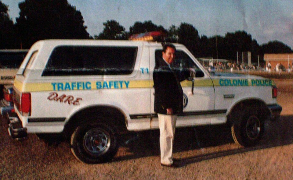 White Colonie Police traffic safety SUV with D.A.R.E. markings, man standing beside open door