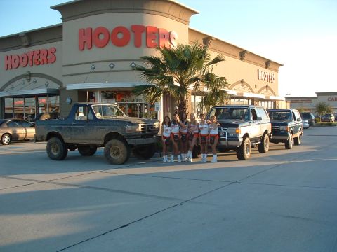 1993 Ford Bronco - Several Ford Broncos are parked outside a Hooters restaurant, with a group of women standing in front of one.