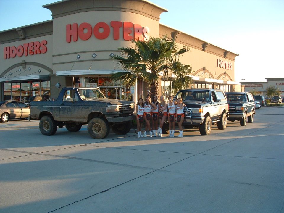 Mud-splattered 1992 Ford Bronco with lifted suspension parked in front of Hooters