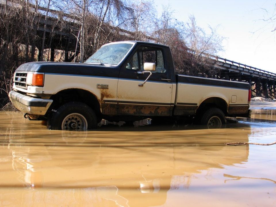 Two-tone pickup truck stuck in muddy water, 1987 Ford F-150