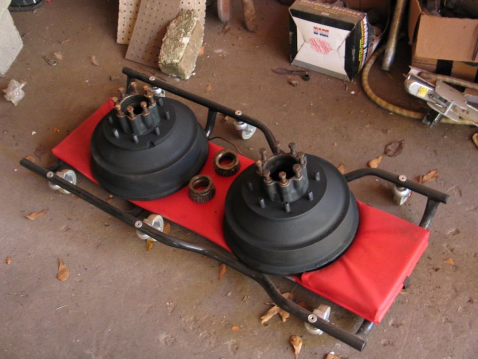 Two black brake drums and bearings on a red creeper