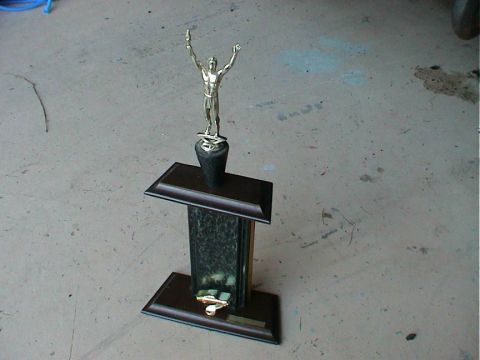 1979 Ford Bronco - A trophy with a male figure is displayed on a concrete floor.