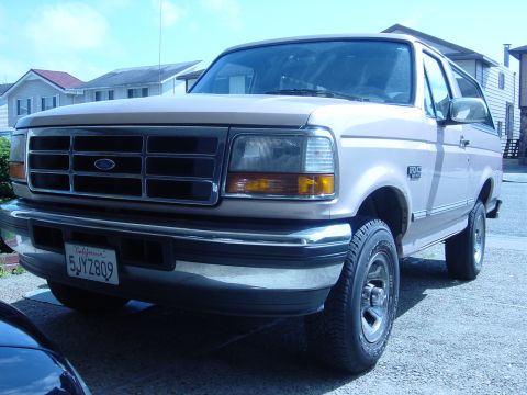 1996 Ford Bronco - The front end of a tan 1996 Ford Bronco is visible, parked on a paved surface.