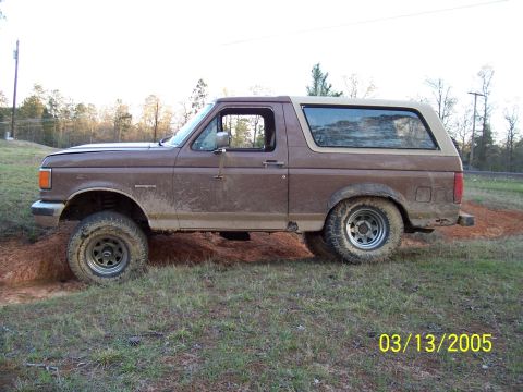 1987 Ford Bronco - This 1987 Ford Bronco is shown in profile while navigating a muddy, grassy terrain.