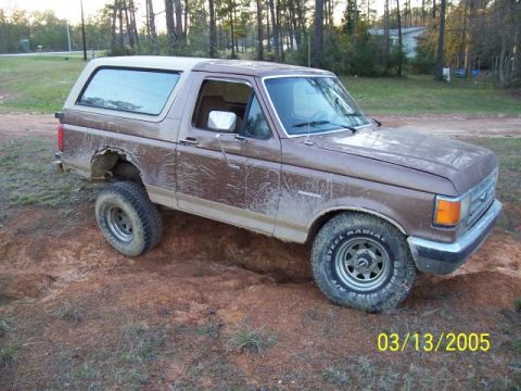 1987 Ford Bronco - This 1987 Ford Bronco is shown off-road with mud splattered on its body.