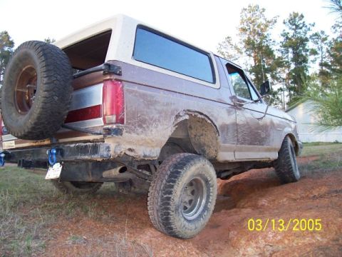 1987 Ford Bronco - This muddy 1987 Ford Bronco is shown from the rear, with a spare tire on the tailgate.