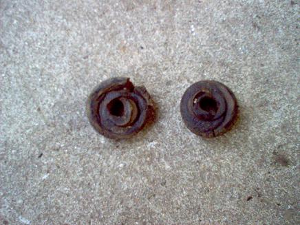 1988 Ford Bronco - Two worn rubber bushings, likely from a vehicle's suspension, lie on a concrete surface.