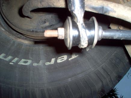 1988 Ford Bronco - A close-up view of a vehicle's suspension system, focusing on a sway bar link and a tire.