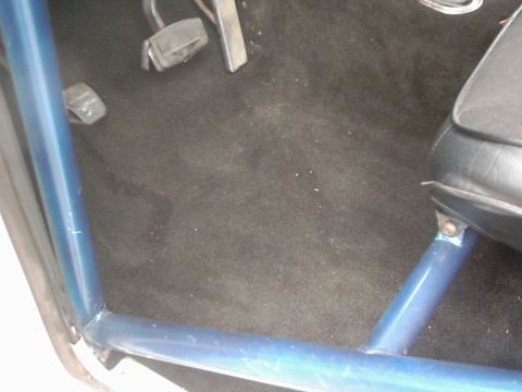 1978 Ford Bronco - Interior view of a vehicle with a blue roll cage and black carpet.