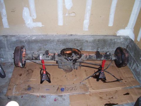 1998 Ford Ranger - Rear axle assembly, likely from a 1998 Ford Ranger, is supported by jack stands on cardboard.