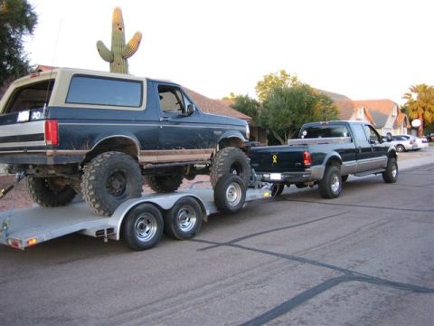 1999 Ford F-250 - Ford F-250 tows a lifted Ford Bronco on a dual-axle trailer.