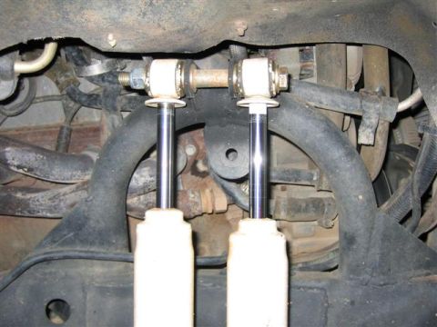 1994 Ford Bronco - Underside view of vehicle suspension system with visible shock absorbers and connecting hardware.