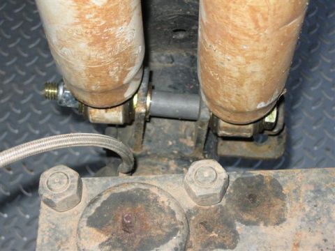 1994 Ford Bronco - Close-up view of shock absorbers and suspension components, including a braided hose and mounting hardware.