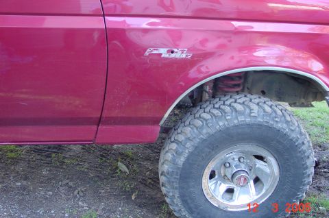1992 Ford F-150 - The side of a red Ford F-Series truck is shown, a prominent F250 badge on the fender above a large, tire.