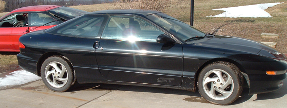 Black coupe with a GT badge on the side, seen from the side