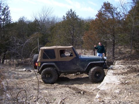 1999 Jeep TJ - A Jeep Wrangler TJ navigates an off-road trail with a person observing the action.