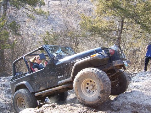 1999 Jeep TJ - A Jeep Wrangler YJ navigates a challenging off-road trail with a rocky incline.