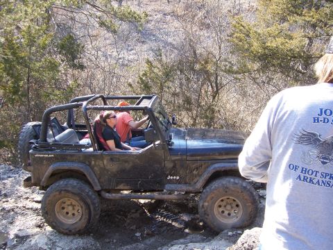 1999 Jeep TJ - A dark blue Jeep Wrangler navigates a rough, rocky terrain during an off-road excursion.