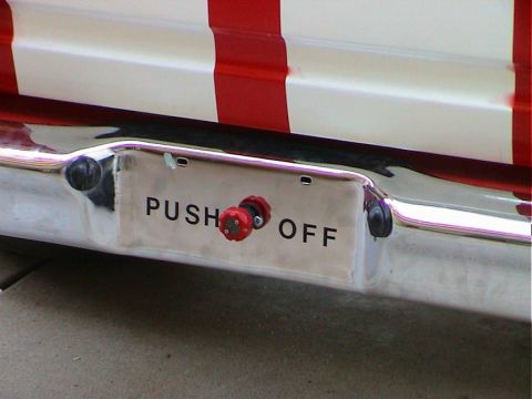 1979 Ford Bronco - Close-up of a vehicle's rear bumper a "PUSH OFF" label and a red knob.