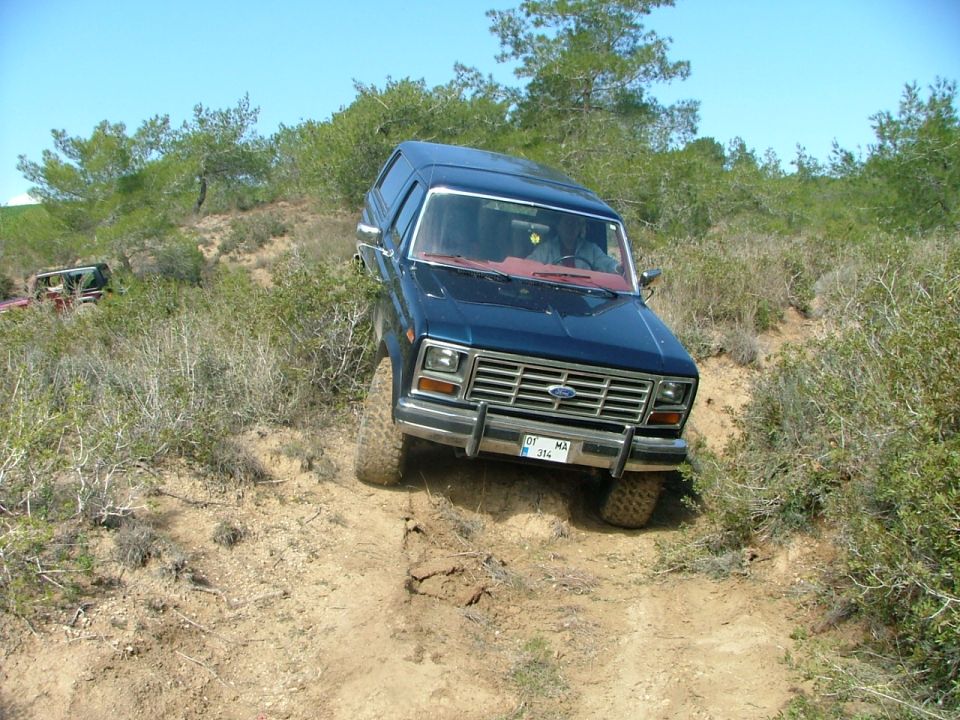 Dark blue Ford Bronco with off-road tires descending a rutted dirt hill, front view, Turkish plate 01 MA 314