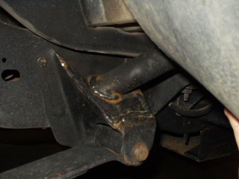 1993 Ford Bronco - Close-up view of the undercarriage of a vehicle, revealing suspension parts and signs of wear.