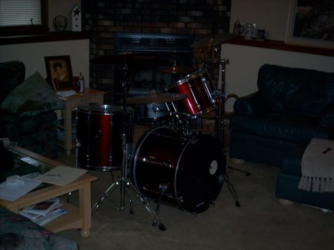1986 Ford Bronco - A drum set is set up in a room with a fireplace and couch.