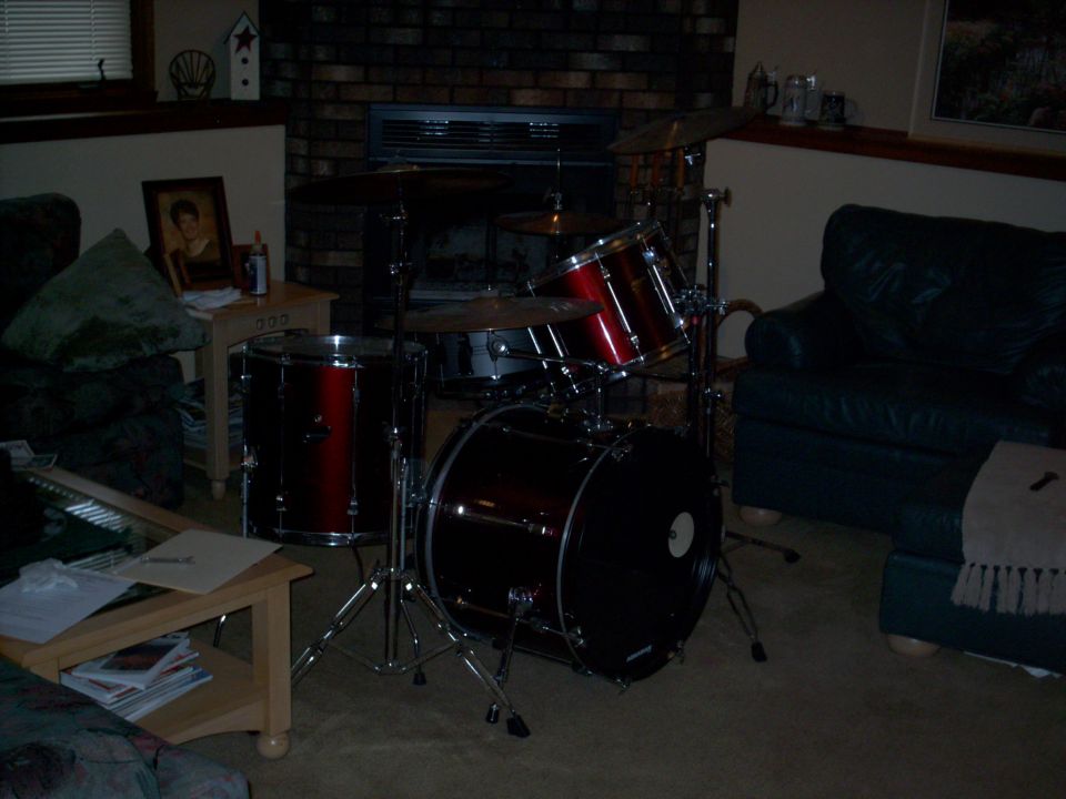 Drum set with red and black drums, cymbals, and stands in a living room