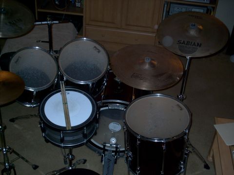 1986 Ford Bronco - A drum kit is set up indoors, multiple drums and cymbals, with drumsticks on the snare.