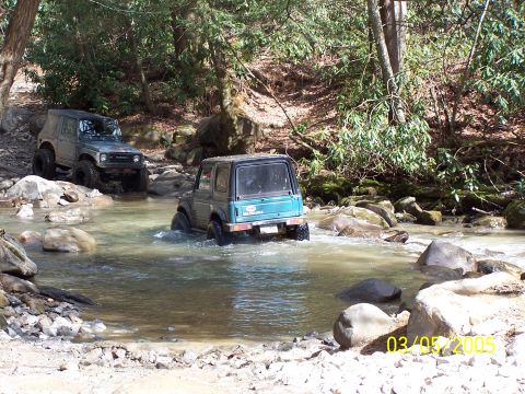 1979 Ford F-150 - Two off-road vehicles navigate a rocky stream bed surrounded by trees, with a date stamp of March 5, 2005 visible.