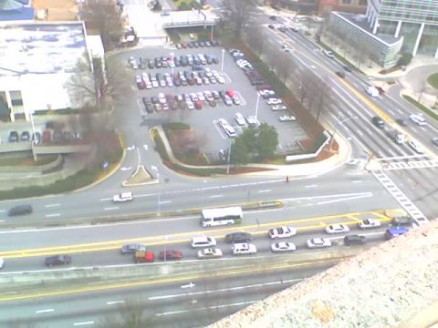 1979 Ford F-150 - A wide shot captures a bustling urban scene with vehicles navigating a highway and filling a nearby parking area.