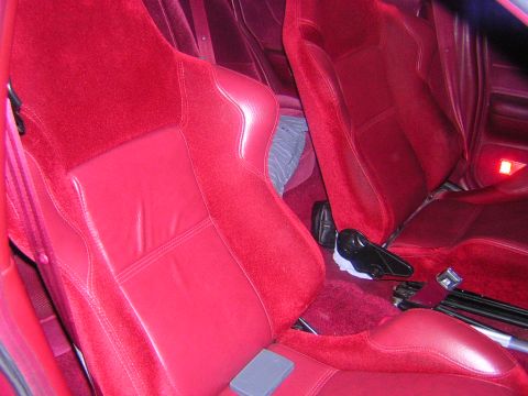 1992 Ford Crown Victoria - Interior view of red leather and velour bucket seats with a manual shifter and handbrake between them, over red carpeting. An amber warning…
