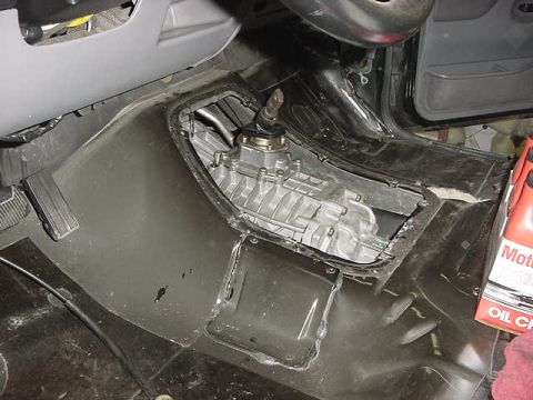 1995 Ford Bronco - Vehicle interior showing the transmission assembly and floor pan, with an oil bottle nearby.