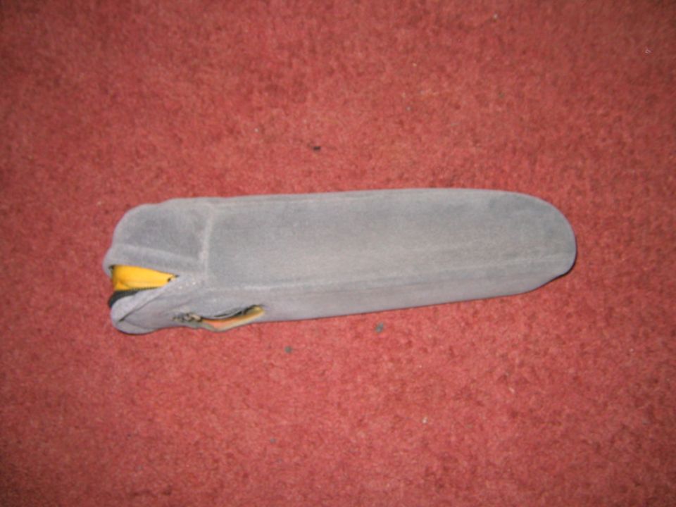 Gray vehicle sun visor with broken yellow clip lying on red carpet