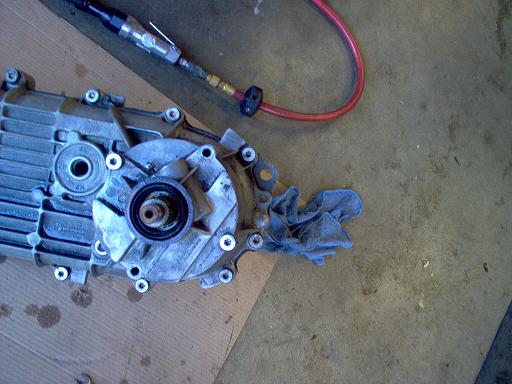 Aluminum transfer case half opened on cardboard during a rebuild in a garage